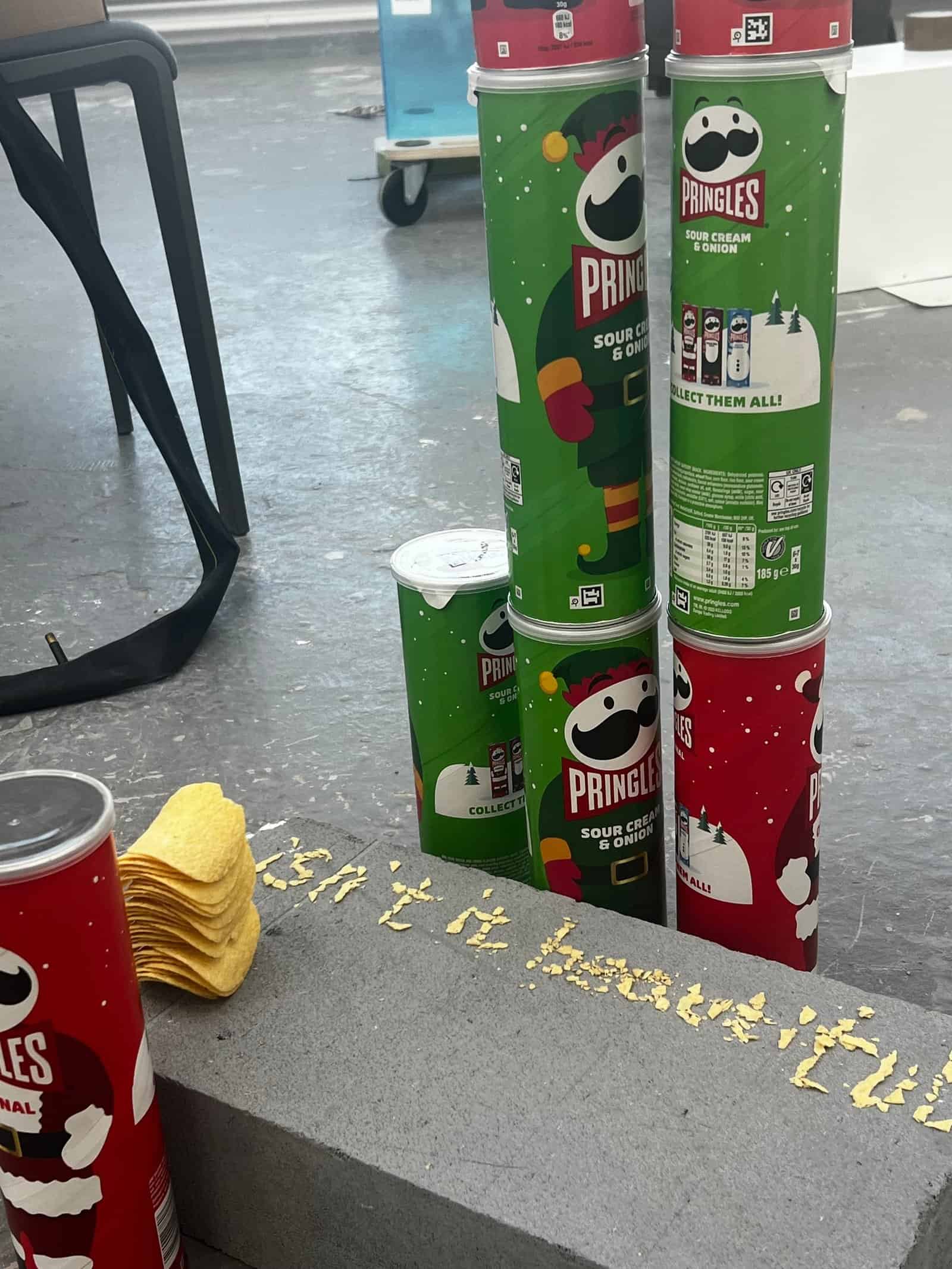 Close view of stacked red and green Pringles cans, a tower of crisps and the words Isn’t It Beautiful.