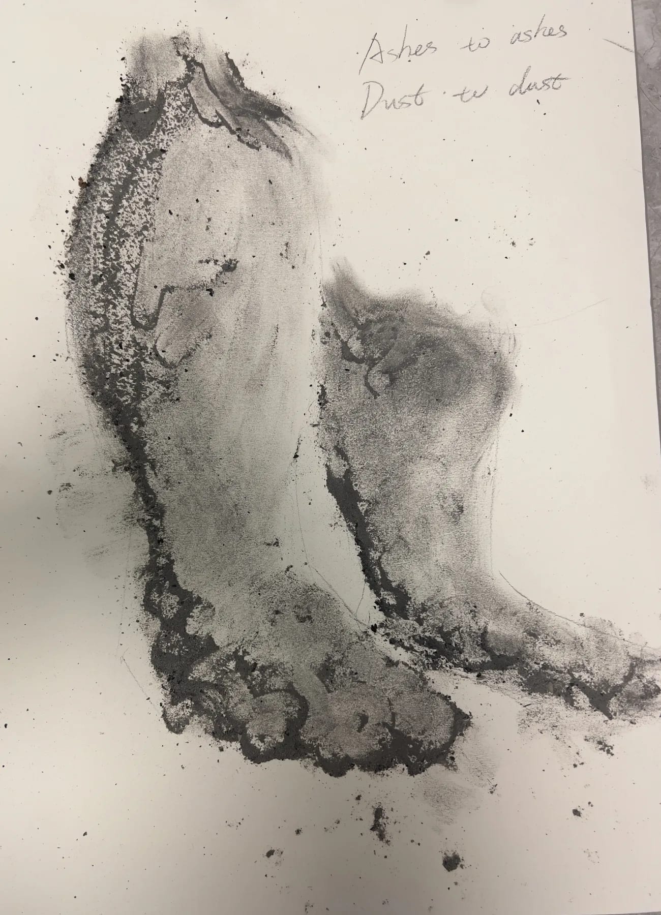 A body-like grey imprint made with cigar ash on white paper.