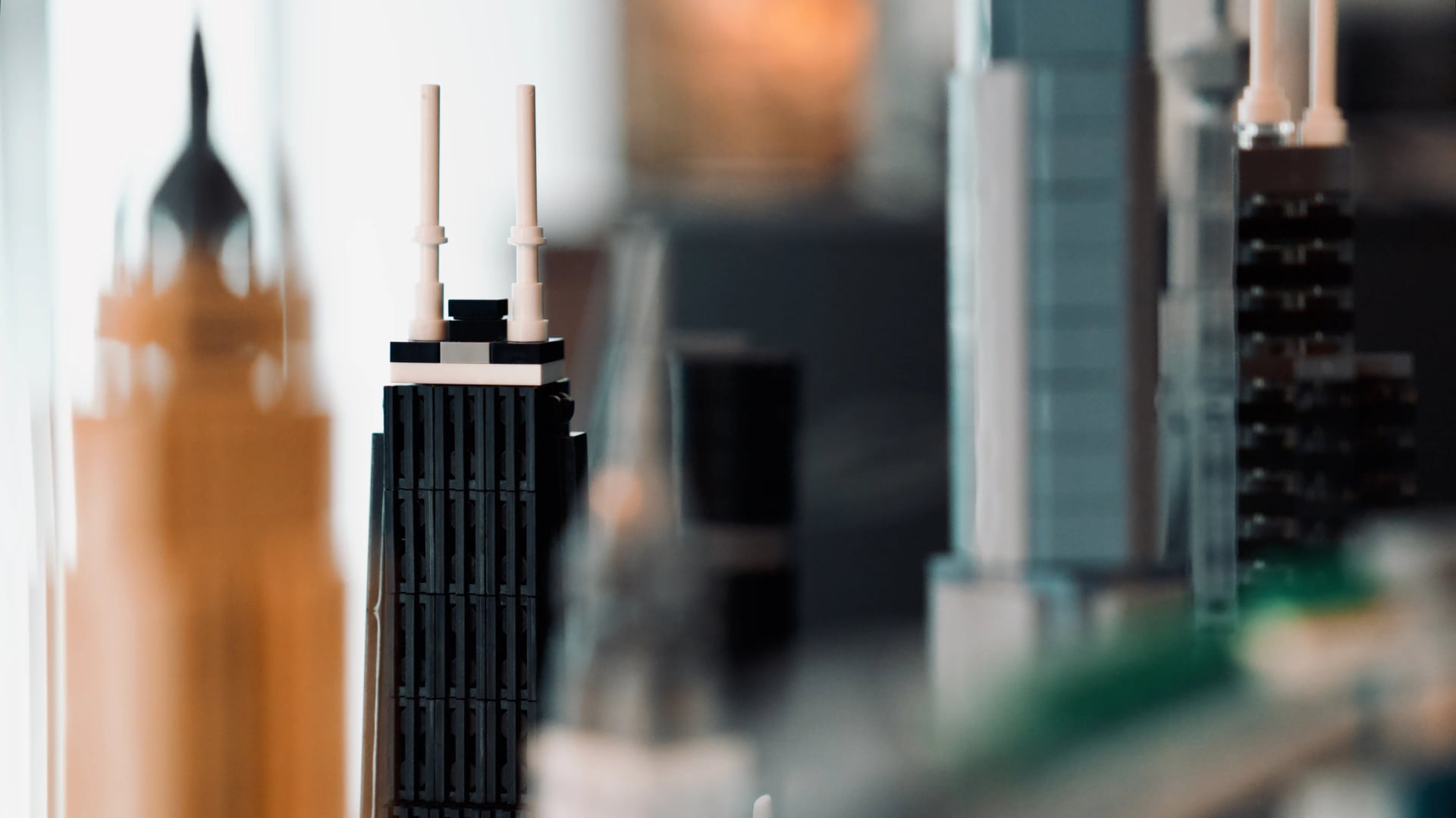 Black LEGO skyscraper with twin white spires among a softly focused modular city.