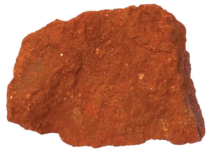Close-up of a chunk of natural red earth used as pigment, referencing soil, labor, and memory.