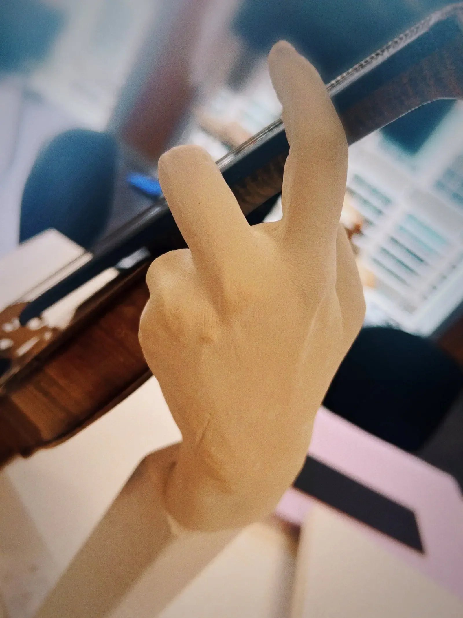 Detailed view of the sculptural hand and its fingers resting on the violin strings.