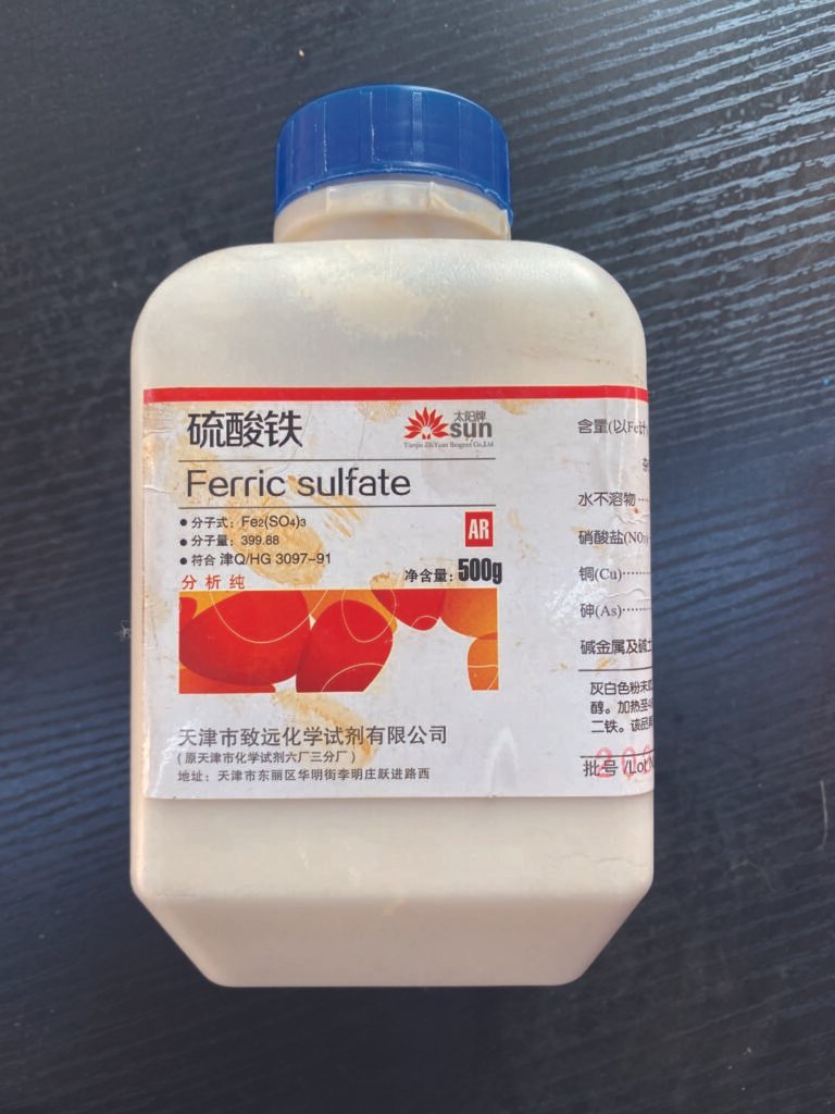 Bottle of ferric sulfate used as a pigment and oxidizing agent in the artist’s experimental painting process.