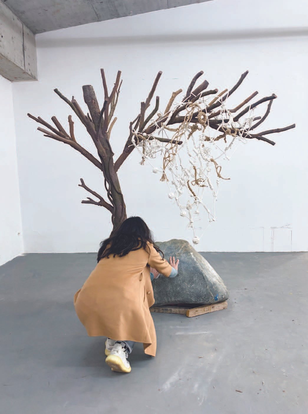 Artist caught mid-action pushing the carved stone in gallery space.